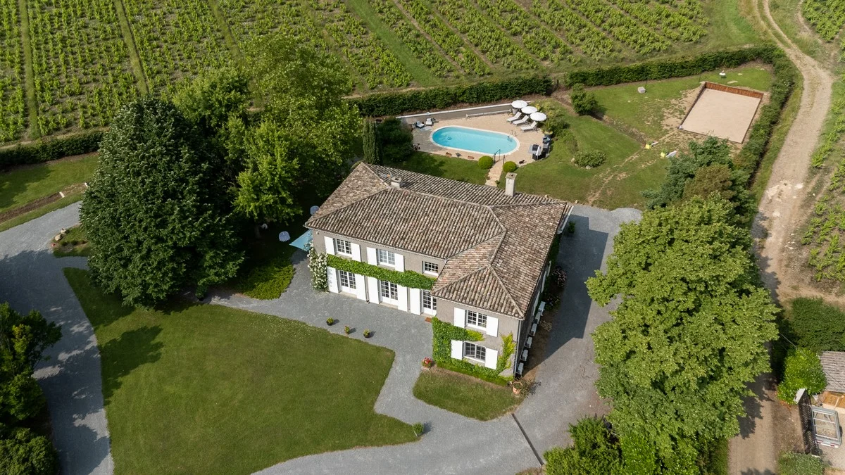 La piscine et sa terrasse en bois, entourées de verdure