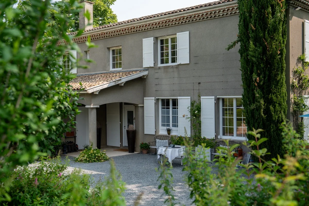 Façade de la Villa Saint-Lager entourée de verdure et volets
