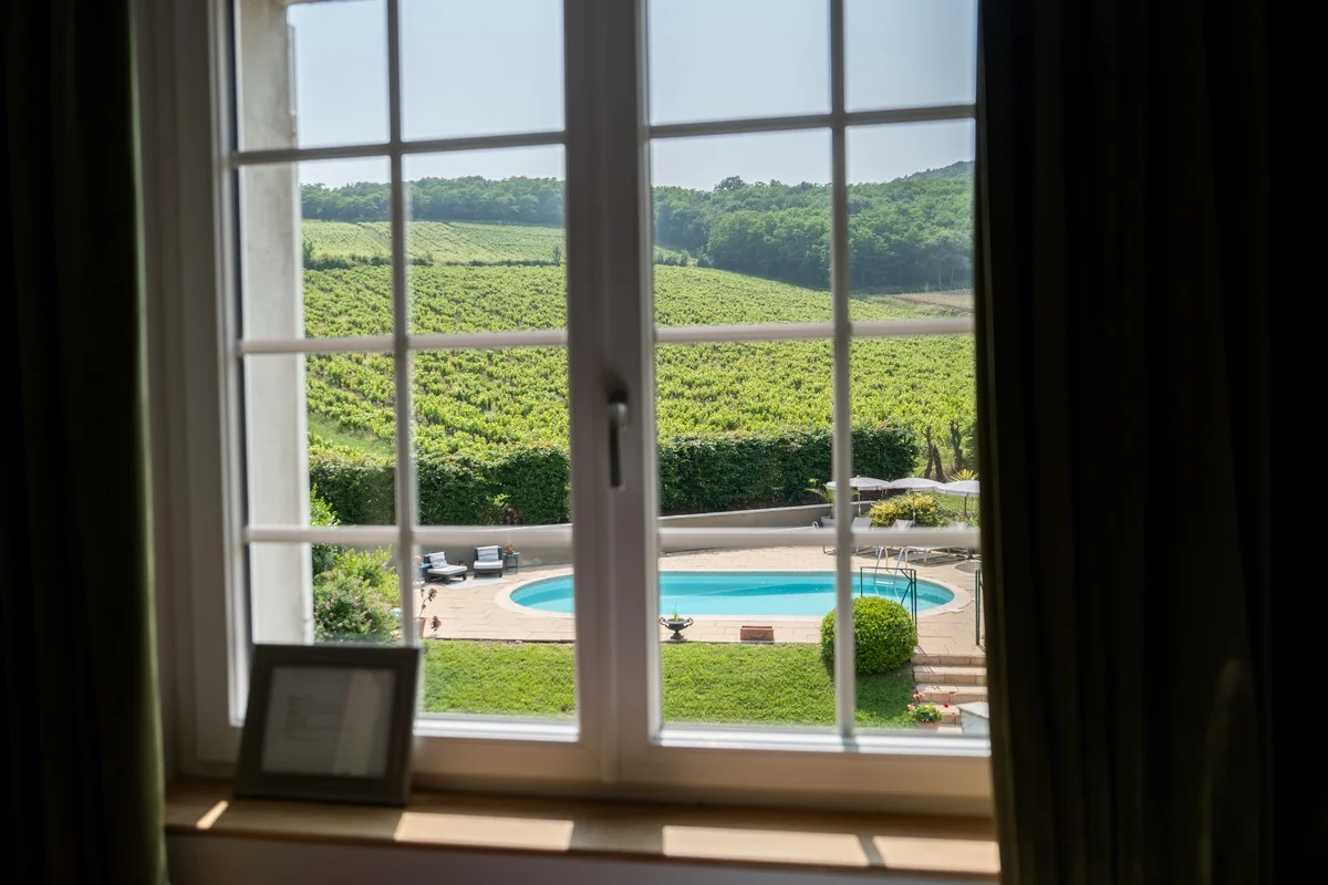 Vue depuis la fenêtre d'une chambre sur la piscine et les vignes du Beaujolais
